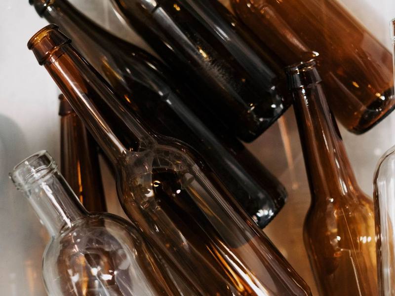 Empty brown and clear glass bottles lying in a plastic bin
