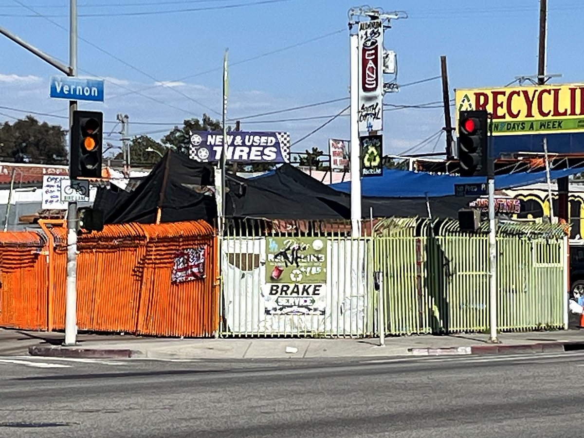 The DÀJÉS yard from the corner of Vernon Ave: orange and green fence, RECYCLING sign above