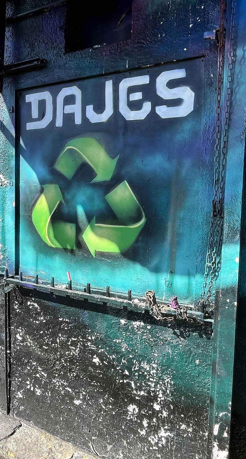 A painted DAJES wall sign with a green recycling symbol